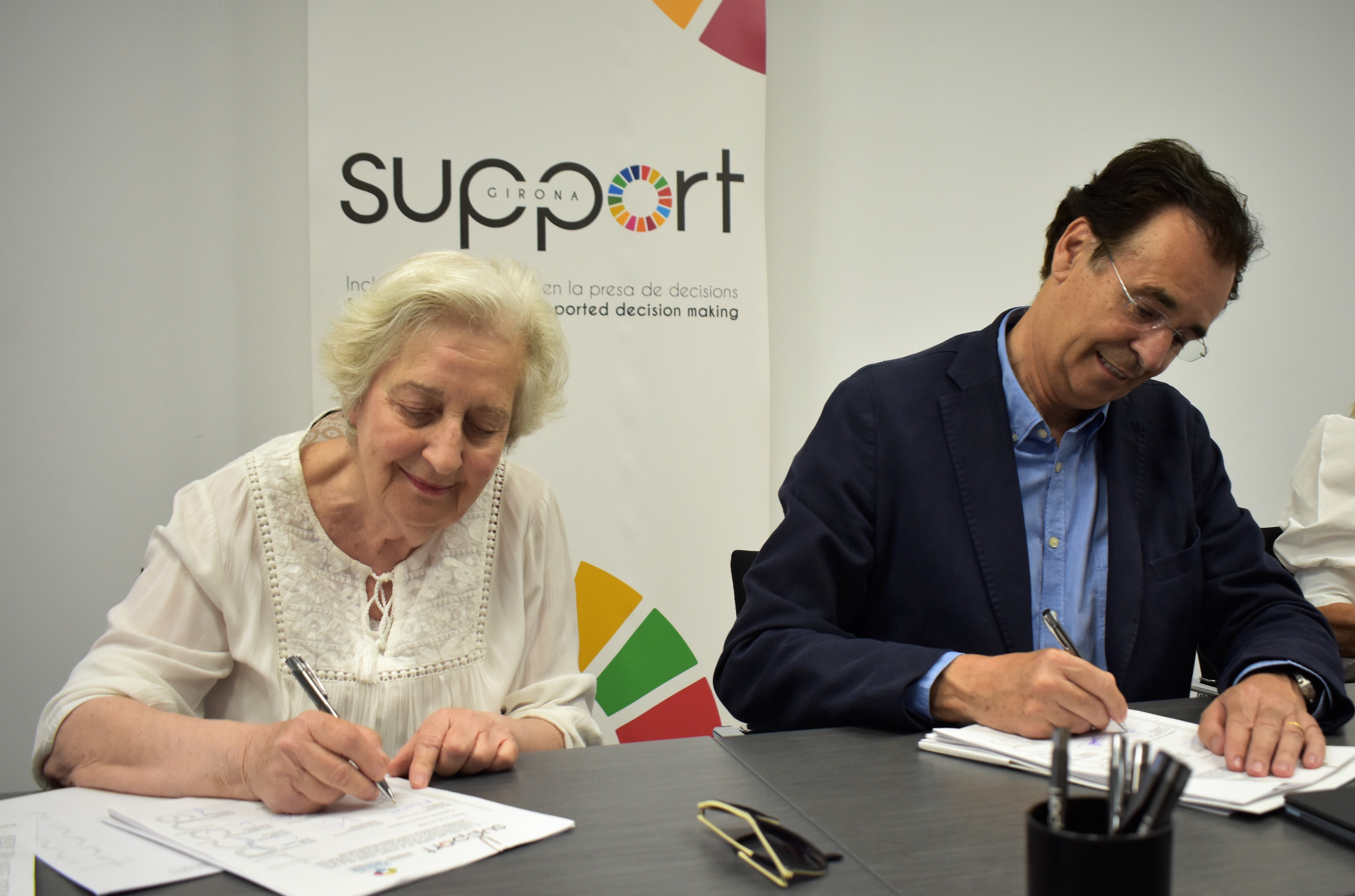 Una dona i un home signant. Són la presidenta de la Fundació Tutelar Fadesia i el president de Support-Girona